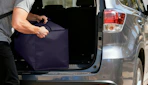 a person puling a moving bag out of a trunk
