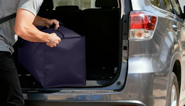 a person puling a moving bag out of a trunk