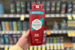 person holding a bottle of body wash in front of a shelf