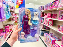hand holding a disney frozen else fashion doll set in a target aisle