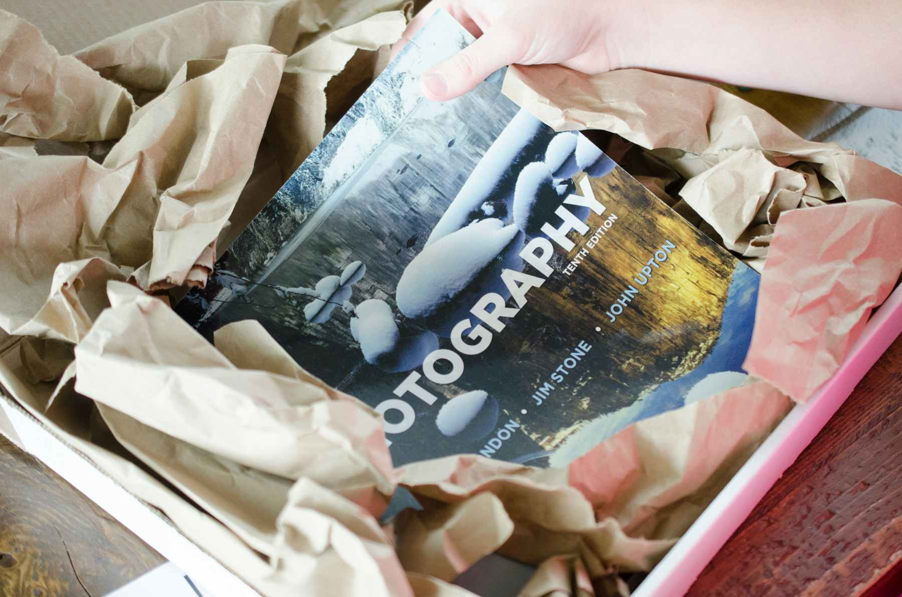 A person taking a photography book out of a box.
