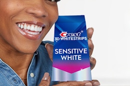 Woman holding the Crest 3D Whitestrips Sensitive At-Home Teeth Whitening Kit in hand.