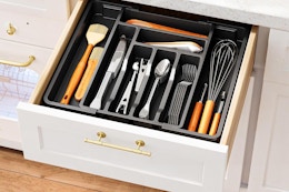 A drawer is open to reveal an expandable silverware organizer full of organized silverware.