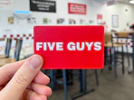 a hand holding a Five Guys gift card at Five Guys