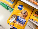 hand grabbing a pedigree dog food bag off a target shelf