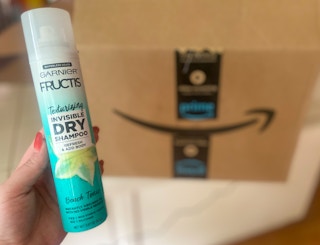 hand holding a can of garnier texturizing dry shampoo in front of an amazon box