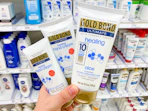 hand holding 3 gold bond healing hand creams in front of target shelf