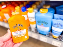 hand holding a yellow container of Gold Bond powder