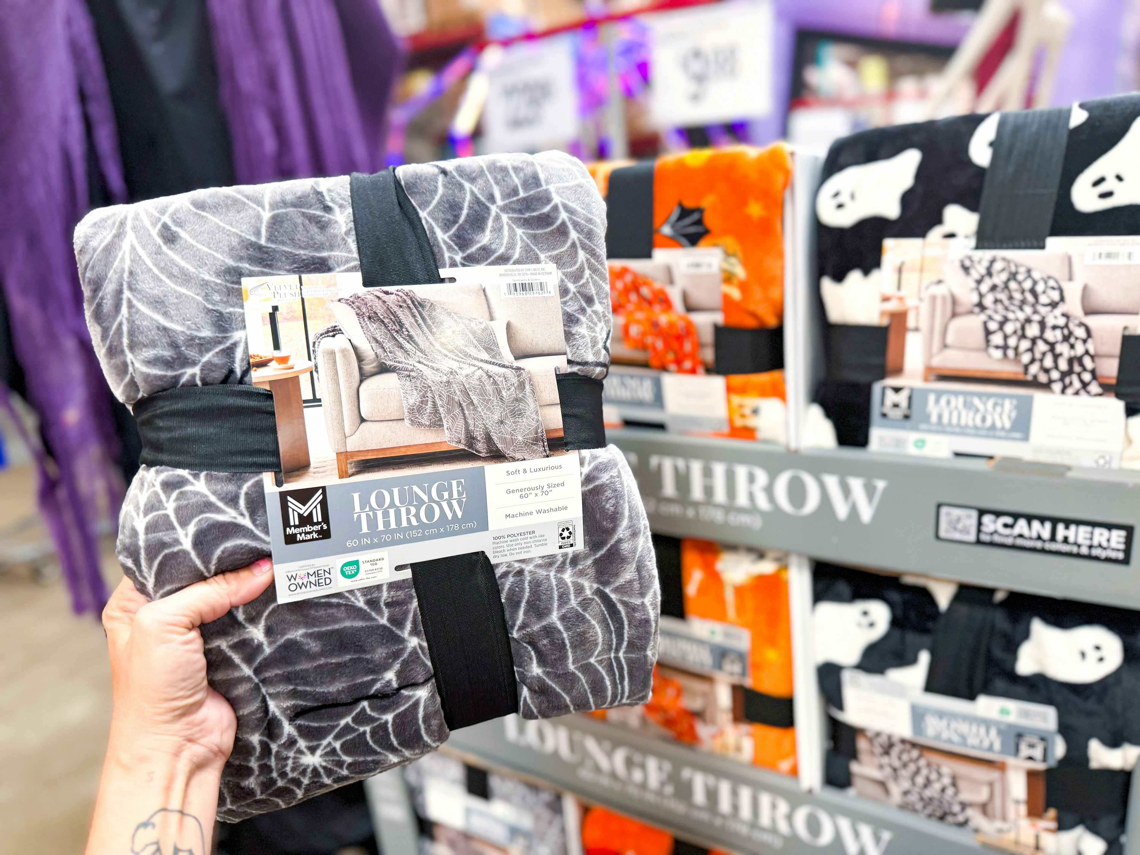 person holding a halloween throw blanket in front of the display