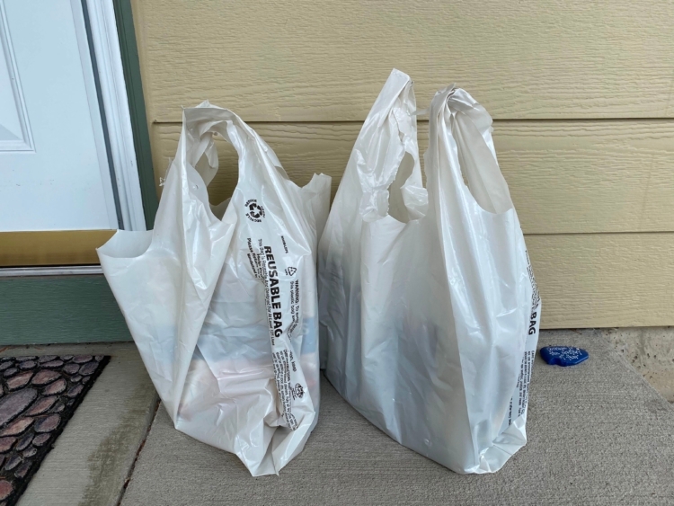 plain plastic bags with items in them sit on a front porch