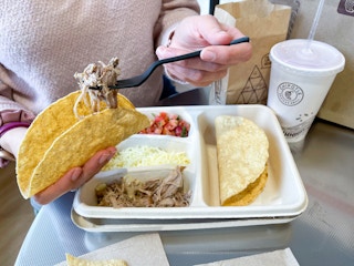 someone filling taco above kids meal