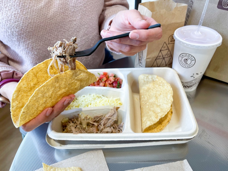someone filling taco above kids meal