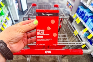 person holding a box of neutrogena acne blemish patches over a cvs cart