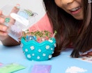 a young girl opening a terrarium playset on a table