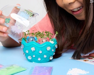 a young girl opening a terrarium playset on a table