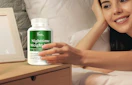 a person holding a bottle of supplements next to their bed