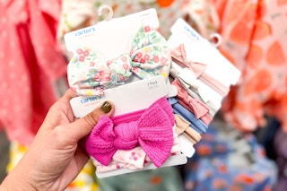 Baby headbands held up in front of baby apparel at Target