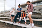 Lifestyle image of a group of kids wearing backpacks outside in front of bleachers