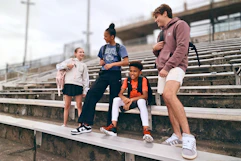 Lifestyle image of a group of kids wearing backpacks outside in front of bleachers