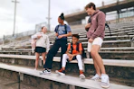 Lifestyle image of a group of kids wearing backpacks outside in front of bleachers