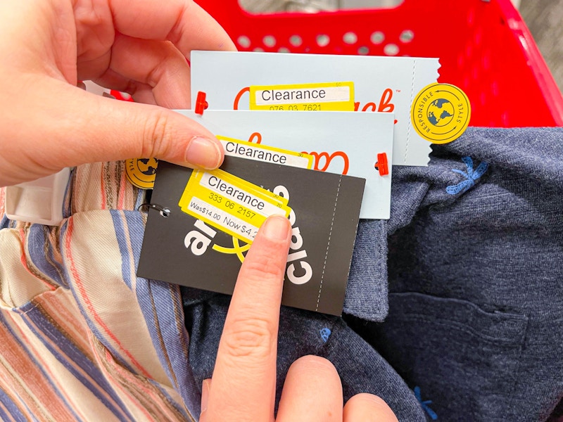 A person's hands holding some Target clearance clothing and pointing to the clearance sticker on one of the tags.