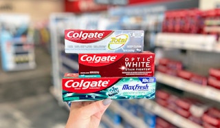 hand holding three boxes of Colgate toothpaste