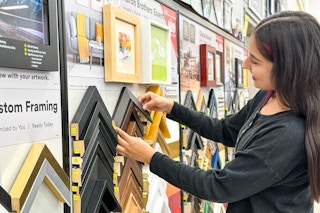 a woman looking at frame samples in the michaels custom framing department 