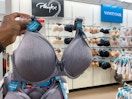 someone holding a bra on a hanger on a rack full of bras in the bra section