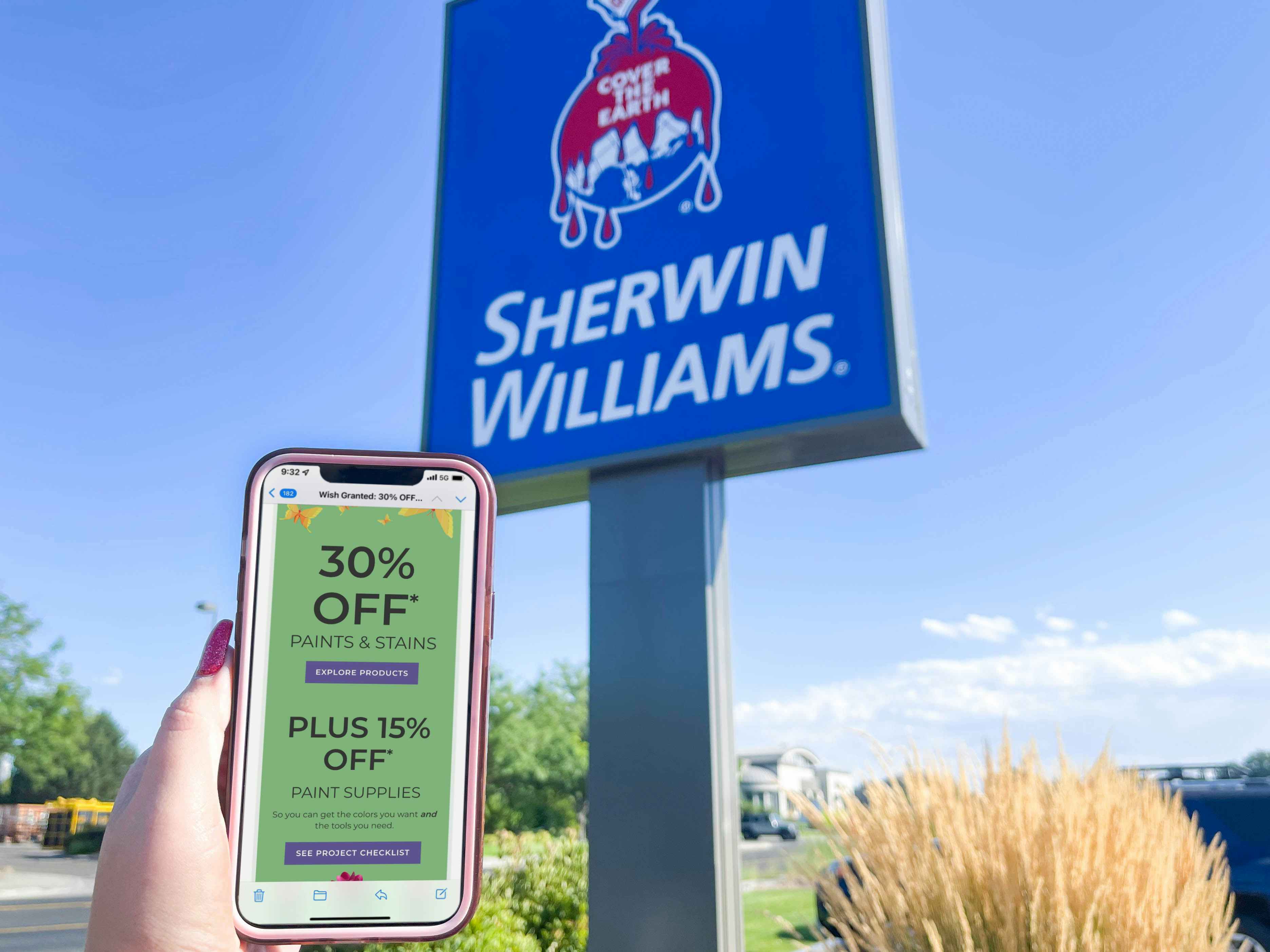 cellphone being held in front of sherwin williams store sign with email coupon on screen