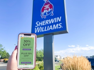 cellphone being held in front of sherwin williams store sign with email coupon on screen