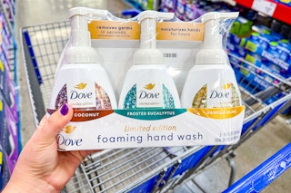 person holding a set of dove hand soaps over a cart