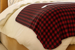 Lifestyle image of a red plaid Sunbeam Heated Microplush Blanket on bed