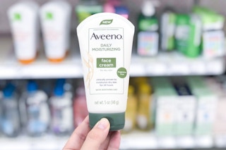 hand holding a bottle of aveeno face cream in a store aisle