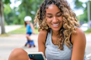 a mom on her phone with a child rollerskating in the background 