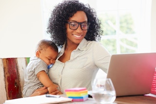 mother at home with her baby while browsing on computer