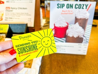 someone holding a panera bread yellow gift card
