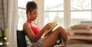 A person sitting by a window reading a book