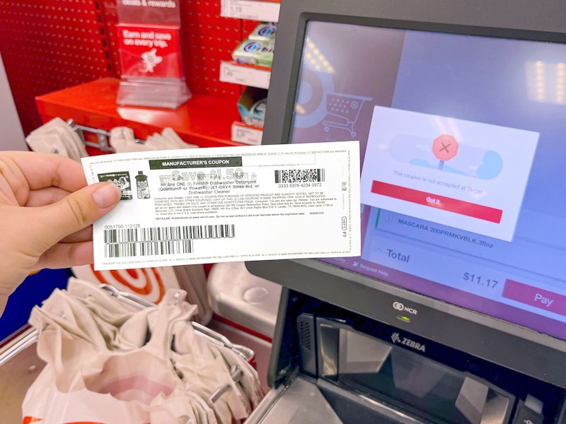 person holding up a rejected manufacturers coupon next to a target checkout screen