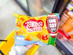 hand holding totino's pizza rolls above a yellow shopping basket