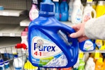 person holding a bottle of purex detergent 