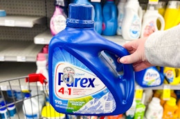 person holding a bottle of purex detergent 