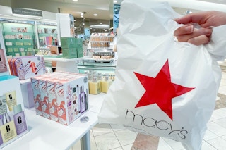 someone holding a macy's shopping bag in the beauty section