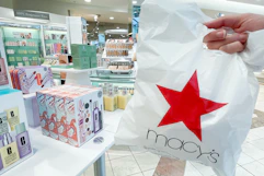 someone holding a macy's shopping bag in the beauty section