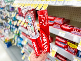 hand holding colgate toothbrush & toothpaate