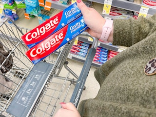holding colgate toothpaste and putting in walgreens cart