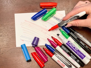 holding a bunch of dry erase markers without the caps