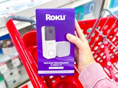 hand holding a roku video doorbell in front of a target cart