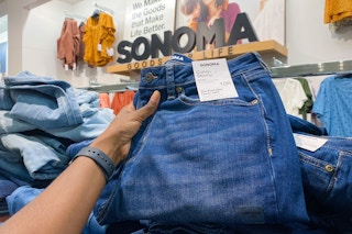 Hand holding a pair of Curvy Skinny Sonoma jeans in front of other jeans