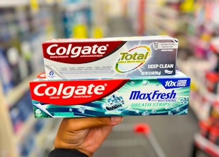 hand holding a box of Colgate Total and Colgate MaxFresh toothpaste