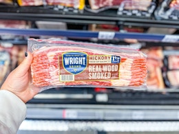 hand holding a pack of wright brand bacon in walmart aisle